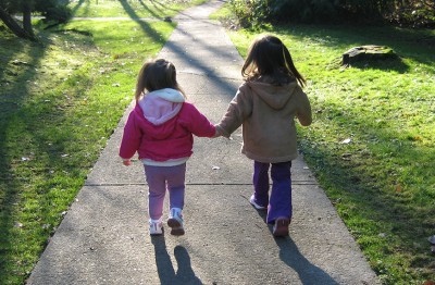 Sisters holding hands on sidewalk