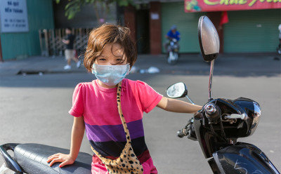Child on motorcycle wearing mask