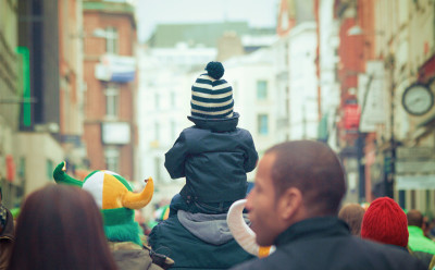 child on persons shoulders in city
