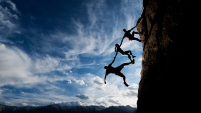 People climbing a mountain, trusting the person at the top to help them to the top