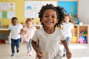 A smiling child runs toward the camera in a classroom, with three other children running behind. The room is bright and colorful, decorated with childrens artwork on the wall.