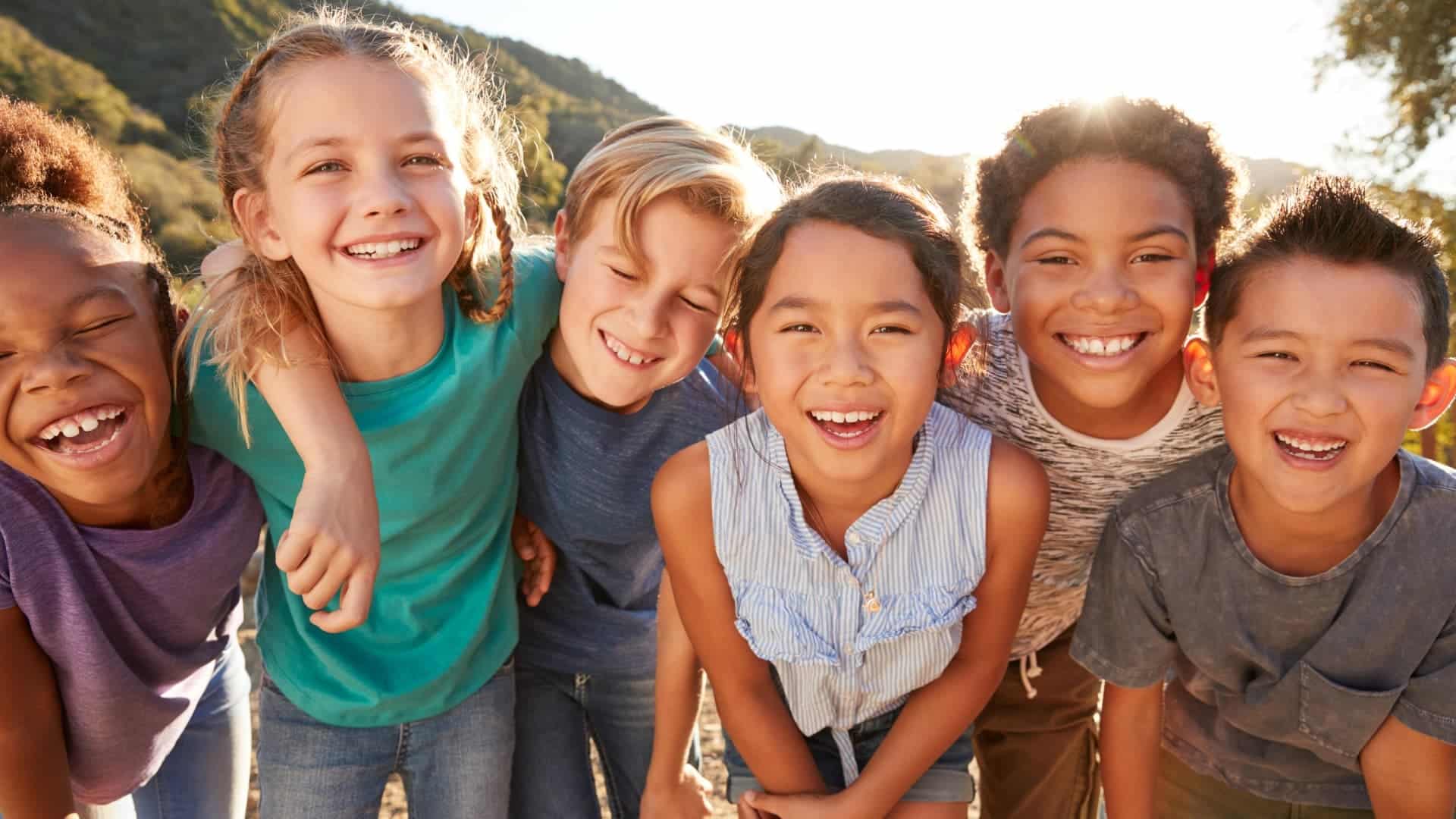 Culturally Diverse Children Smiling in a group with arms around each other