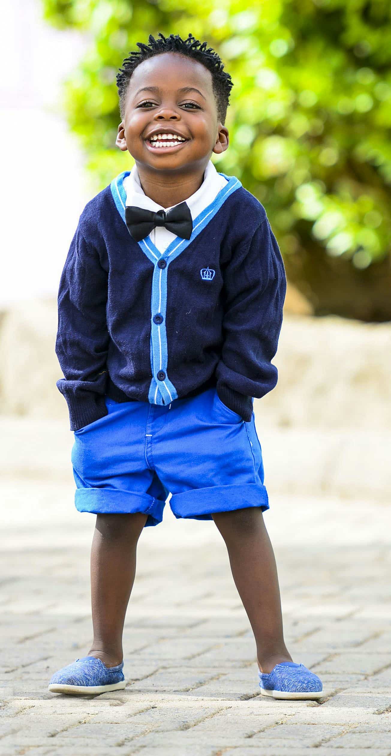 Smiling young boy in with trees at the background.